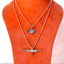 Load image into Gallery viewer, Silver necklace with a pendant on an orange mannequin bust.